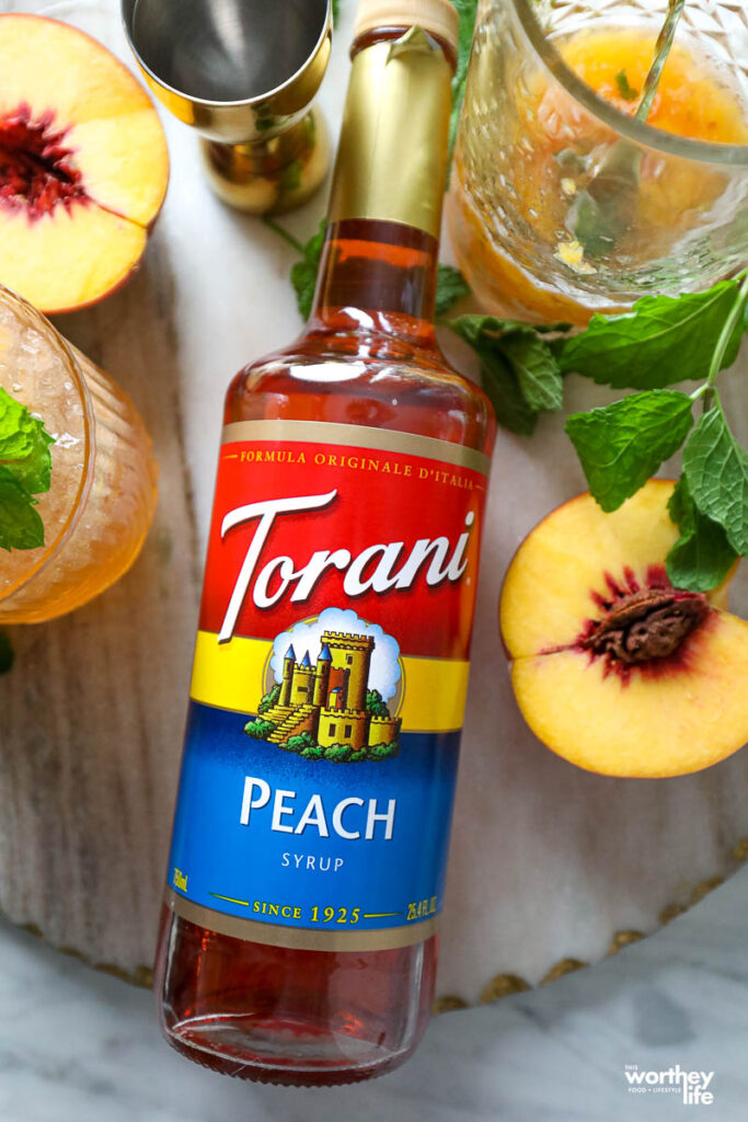 torani peach syrup surrounded by fresh peaches