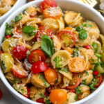 A white serving bowl filled with our summer toamto pasta salad.