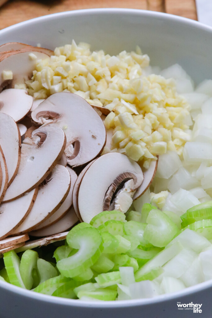 A white bowl with mushrooms, celery, and onions.