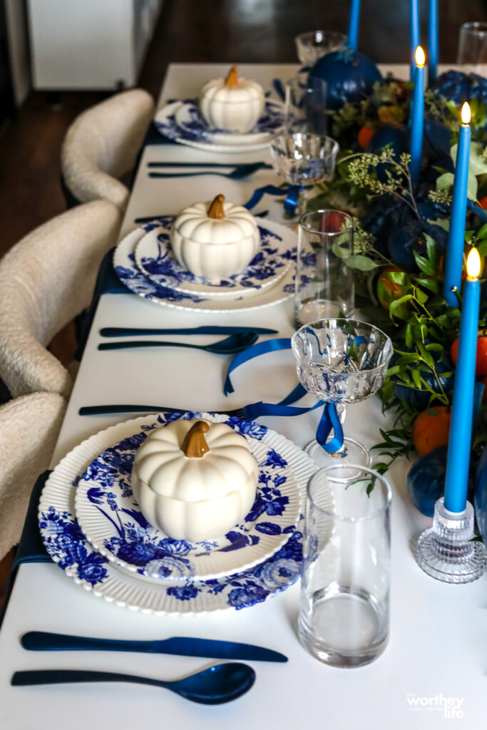 a set of white pumpkins on blue and white floral plates on a white table for thanksgiving