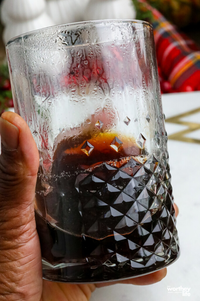 man holding a glass jar with spiced syrup