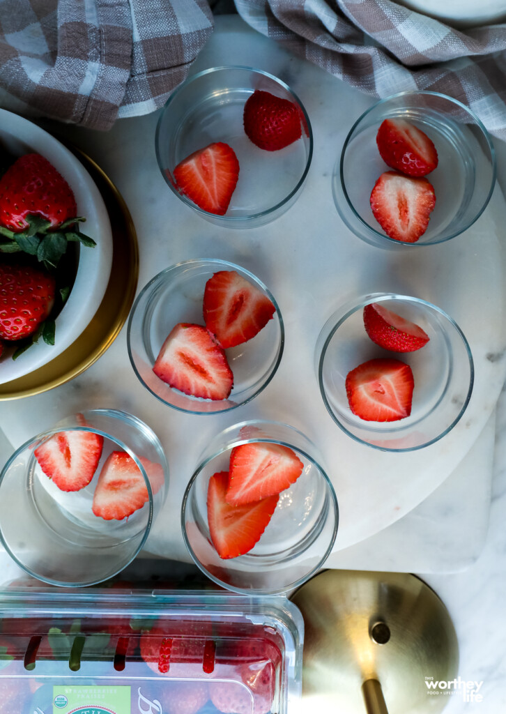 adding strawberries to a glass cup